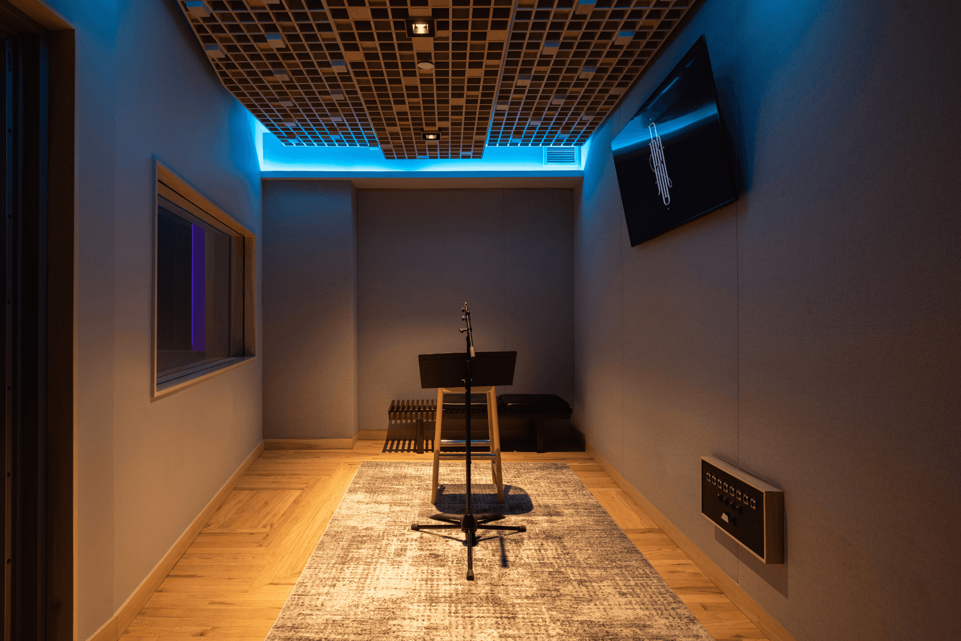 Secondary booth and writing area inside Studio B with stool seating and a wall display.